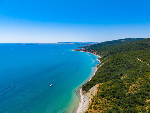 Beautiful coastal view showing clear water and a winding shoreline with boats in the distance on a sunny day in a coastal area