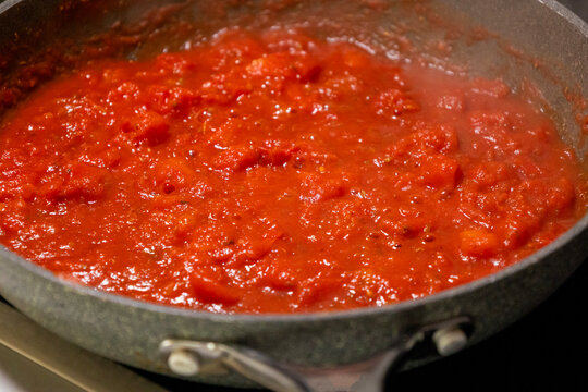 Close-up of fresh, flavorful tomato sauce simmering and bubbling gently in a rustic frying pan
