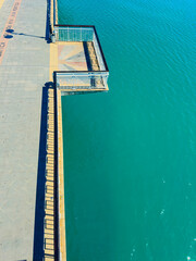 Fototapeta premium Building structure extends over water in a coastal area with bright colors during daylight hours showing clear blue water
