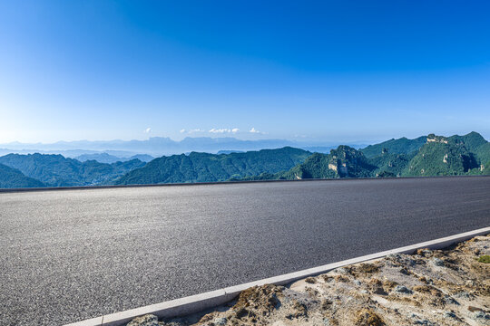 Empty asphalt road leading to distant mountain range under a clear blue sky in Zhangjiajie, Hunan, China