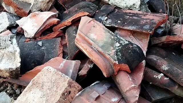 High angle close up shot focusing on a messy pile of shattered orange clay shingles moving gently.