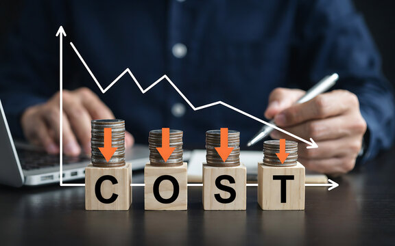 Businessman analyzing cost reduction strategies with declining coin stacks and graph