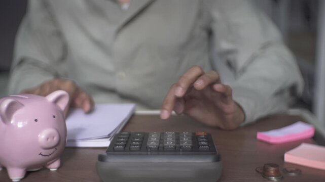 People use a calculator and write a financial report, recording income, expenses savings and deductions to manage costs and maintain an accurate budget balance.