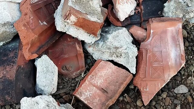 High angle close up shot showing a layered pile of concrete fragments and broken clay shards moving lightly.