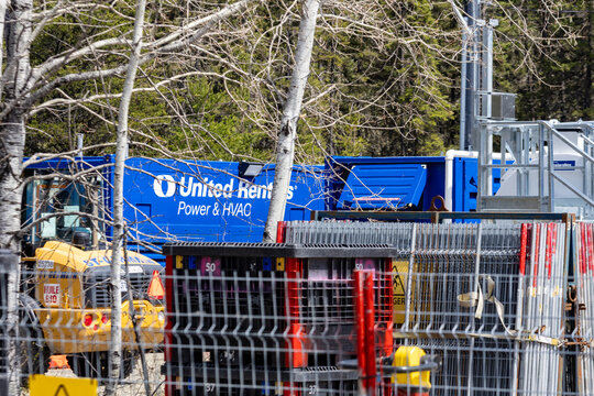 Parents, Quebec, 21 May 2026 : A blue United Rentals Power & HVAC container stands near yellow construction machinery and metal fencing.