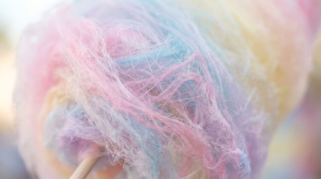 Soft pastel colored cotton candy spun sugar wrapped around wooden carnival stick