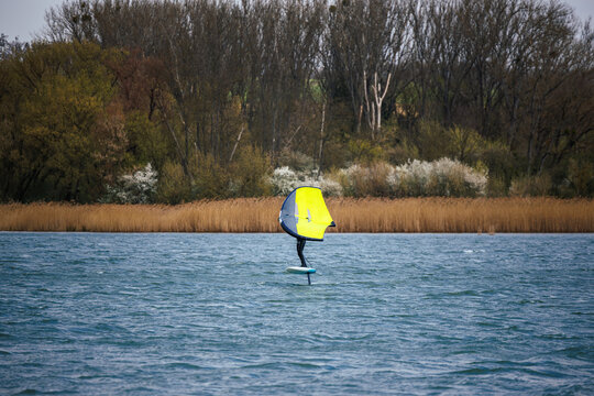Wingfoiling on windy lake. Water sport and adrenaline adventure outdoors