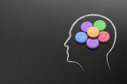 Human head silhouette filled with MDMA or Ecstasy pills on black background