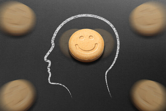 Human head silhouette filled with MDMA or Ecstasy pills on black background