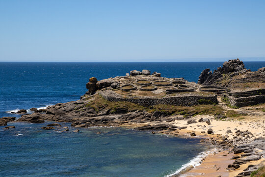 Prehistoric Celtic ruins of Castro de Baro&ntilde;a in Porto do Son, Galicia, Spain. Ancient Iron Age circular stone houses and fort fortress on a rocky coast peninsula facing the blue Atlantic Ocean.