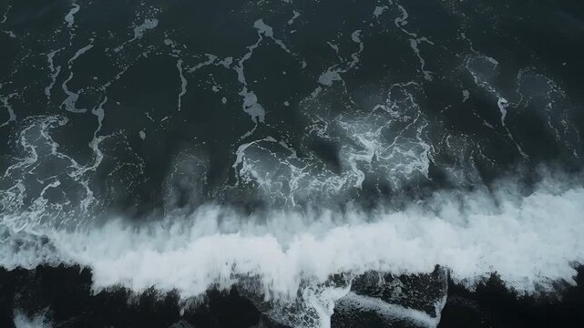 Advancing breaking waves spreading lace-like foam across black sand shoreline, driven by swell