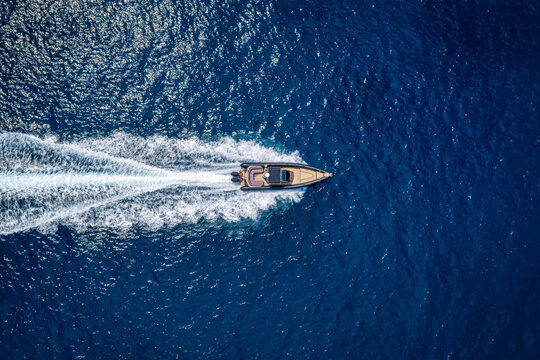 Aerial overhead view of a modern luxury RIB twin outboard motorboat crossing the blue ocean with high speed