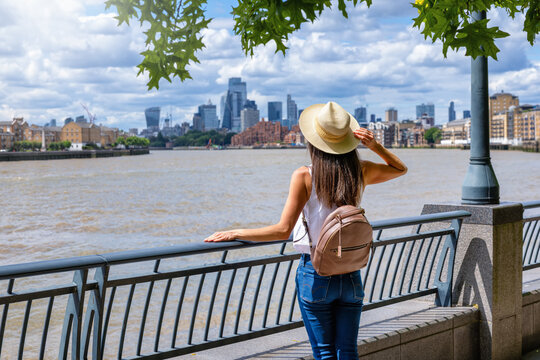 A tourist woman enjoys the view of the London skyline from Canary Wharf during a sunny summer day in England