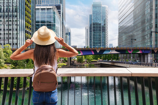 A touroist woman looks at the urban skyline of Canary Wharf, financial district of London, England, during a sunny summer day