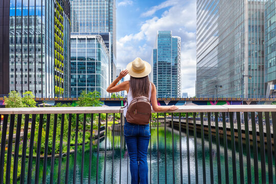 A woman looks at the skyline of Canary Wharf, financial district of London, England, during a sunny summer day