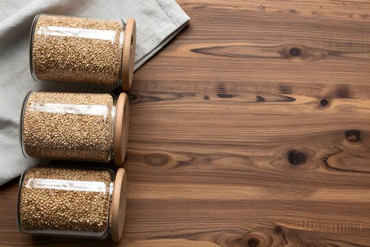 Glass storage jars containing groats are placed on a wooden surface.