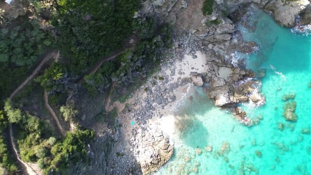 Zambrone, Costa degli Dei, Calabria, Italy. Top down rotating drone footage of turquoise Tyrrhenian Sea, rocky cove and crystal clear water along the Mediterranean coastline.