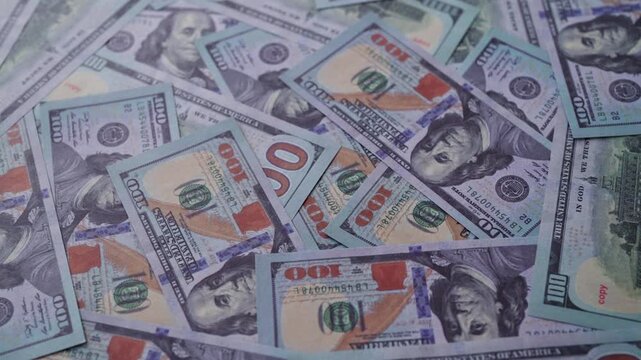 Background of one hundred US dollar bills scattered randomly.