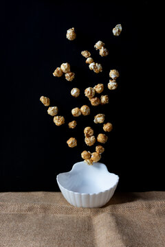 White bowl on a table with popcorn in the air