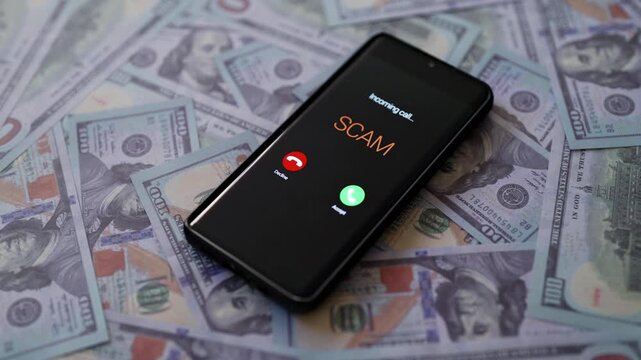 Smartphone showing scam call on screen lying on dollars.