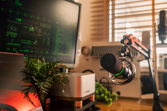 Microphone on a boom arm with a coding monitor, mini PC and mechanical keyboard in a modern home studio