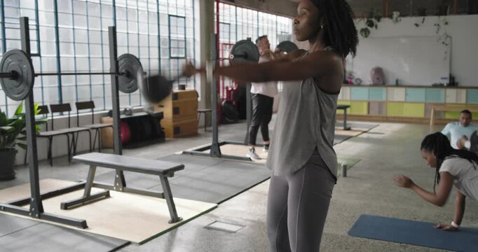 Woman starting session, swinging kettlebell, finishing set, then coaching teammate in loft studio