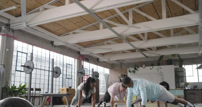 African American friends doing plank to side-plank reps on mats in loft, leader cueing core work