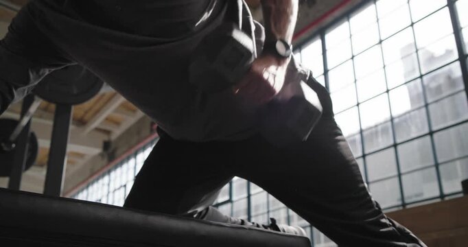 African American man leaning on bench in gym, reaching for dumbbell pulling rows for back strength