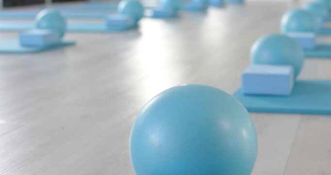 Single blue ball is resting on mat, camera is pulling back to show studio class layout