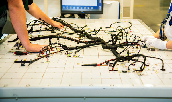 Automotive wiring harness assembly on production line at car manufacturing factory