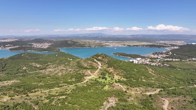 Aerial view flying over a lush green forest revealing the beautiful Ayvalik coastline in Turkey, oe01