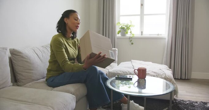 African American woman noticing box on table, lifting, inspecting barcode, probing seam, copy space