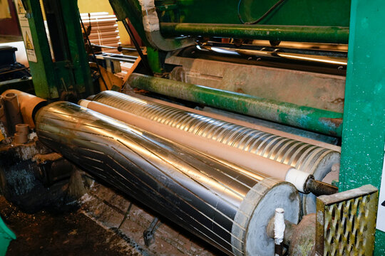 Industrial plant closeup: Large metal rollers, one diagonally grooved, one horizontally striped