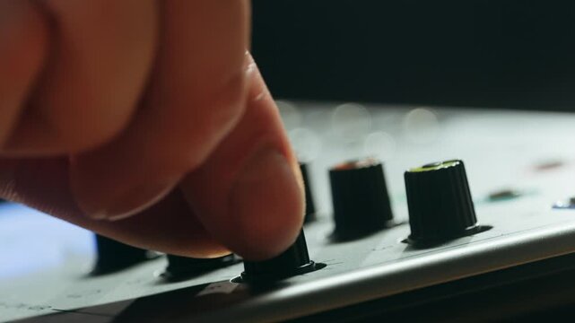 Music studio close up, Close up hands shot of sound engineer using mixing console, remote control for adjusting sound, audio mixer. Musician creates music, makes remix for DJ set. Sound