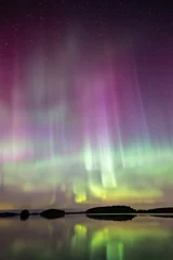 Northern lights dancing over calm lake in Farnebofjarden national park in north of Sweden. © Conny Sjostrom