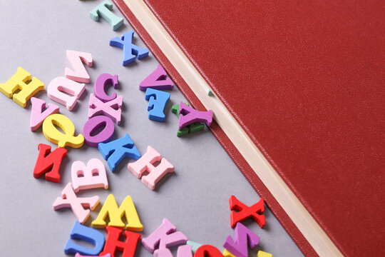 Book with many colored letters on gray background. Education, learning concept.