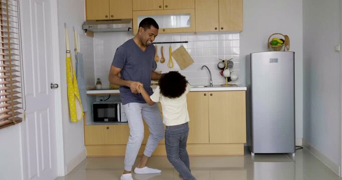 Playful African American father and young son dancing while enjoying fun family time at home together. Cook breakfast morning routine. Single parent Dady home school education concept