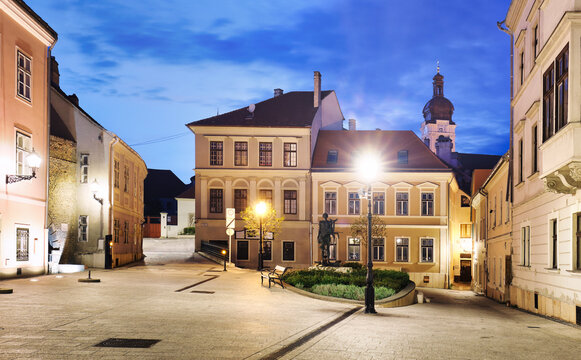 Hungary - Cozy little baroque square in the center of Gyor, with the bronze sculpture of Nimrod, in the background the Cathedral tower at night