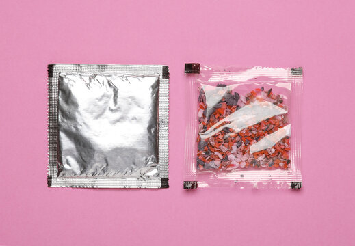 Disposable spice packets on a pink background.