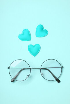 Stylish eyeglasses with red hearts on blue background
