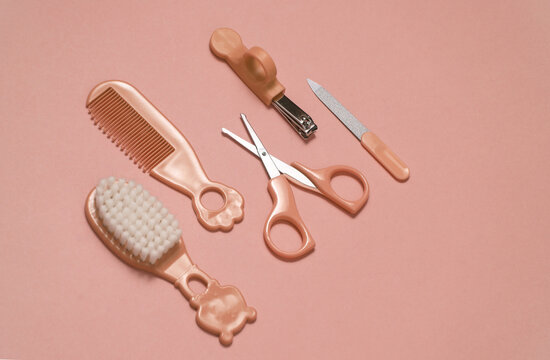 Baby care set on pink background. Scissors, comb, nail file and tweezers. Top view