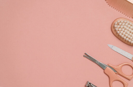 Baby care set on pink background. Scissors, comb, nail file and tweezers. Top view. Copy space