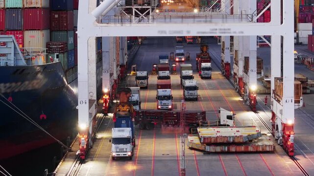 gantry crane loading cargo container from truck to container ship at busy industrial harbor port terminal. Global maritime logistics, freight transportation, and international supply chain trade.