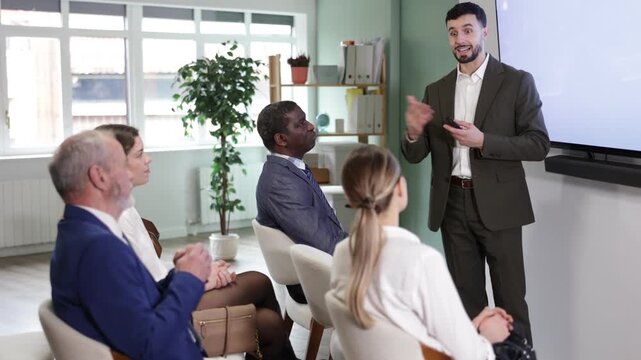  man lecturer with remote controller speaks to business audience of listeners, shares knowledge, communicates with listeners. Speaker reports on changes in companys policy provisions. 