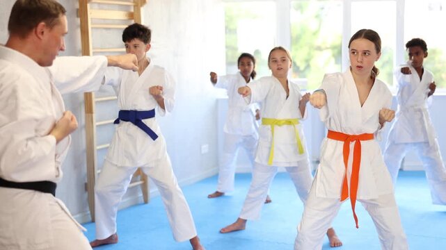 Children of different nationalities in kimono standing in fight stance during group karate training