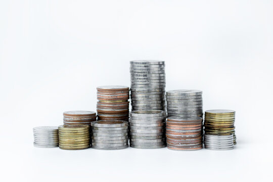 Stacks of assorted coins arranged in different heights on a white background, representing savings, investment, wealth accumulation, financial planning, and business growth. Minimal composition with c