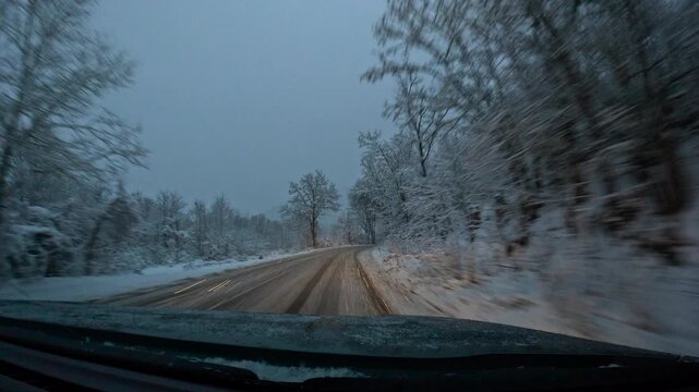 Car driving on snowy road at dawn. Winter road journey through snow-covered forest at dawn, driving inside car and overtaking truck with scenic landscape passing by