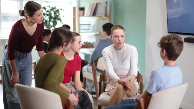 Diverse teenage students working in two separate teams during interactive group discussion in classroom 
