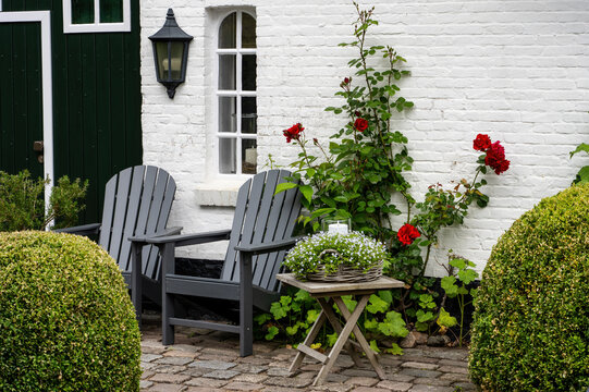 Cozy Cottage Patio with Adirondack Chairs, Red Roses and White Brick Country House