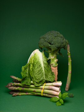 Still life with broccoli, asparagus, and lettuce on a green background